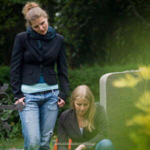 Deux sœurs se soutiennent mutuellement en se promenant dans un cimetière, trouvant du réconfort dans leur deuil.